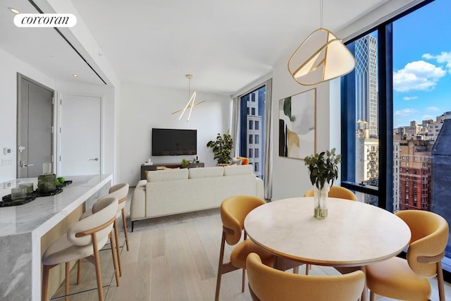 dining area featuring light wood-type flooring and a wall of windows