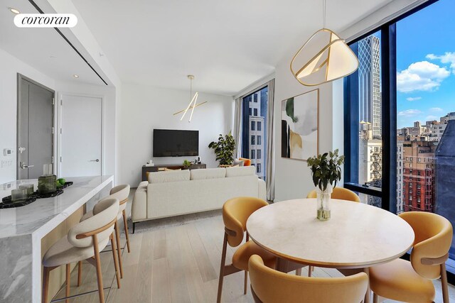 dining room featuring floor to ceiling windows, light wood-style flooring, and visible vents