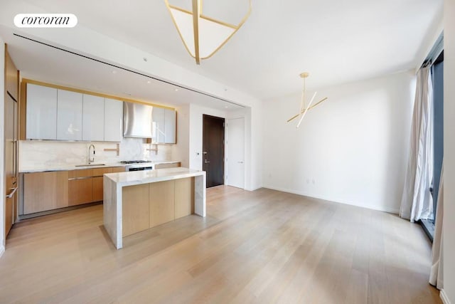 kitchen featuring sink, white cabinetry, backsplash, a center island, and light hardwood / wood-style floors