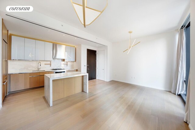 kitchen featuring visible vents, light wood-type flooring, modern cabinets, a sink, and decorative backsplash