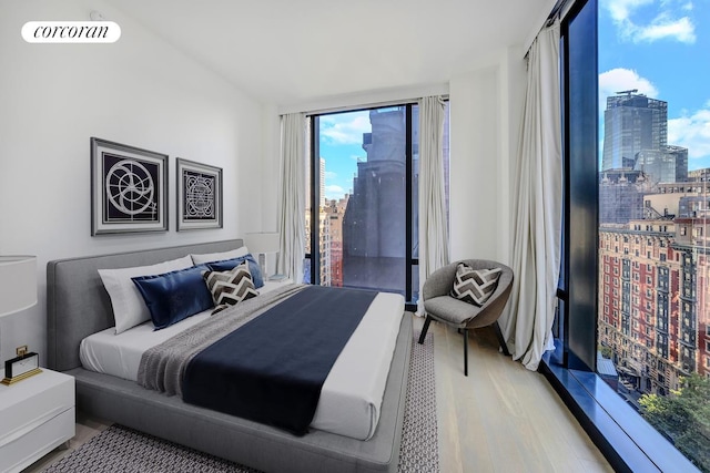 bedroom with a city view, visible vents, access to outside, light wood finished floors, and a wall of windows