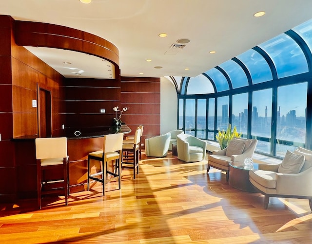 bar featuring recessed lighting, a city view, visible vents, floor to ceiling windows, and light wood finished floors