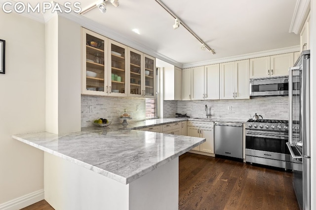 kitchen featuring tasteful backsplash, kitchen peninsula, sink, crown molding, and high end appliances