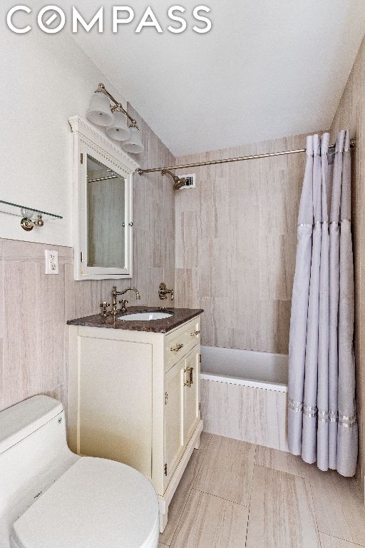 full bathroom featuring toilet, vanity, and shower / bath combo with shower curtain