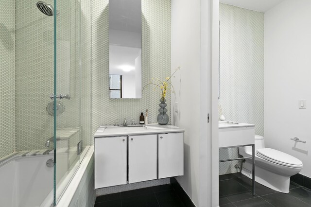 bathroom with tile patterned flooring, vanity, toilet, and enclosed tub / shower combo