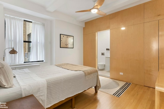 bedroom featuring ceiling fan, connected bathroom, beam ceiling, and light wood-type flooring