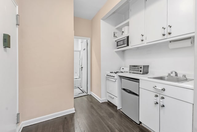 kitchen featuring dark wood-type flooring, a sink, appliances with stainless steel finishes, white cabinets, and light countertops