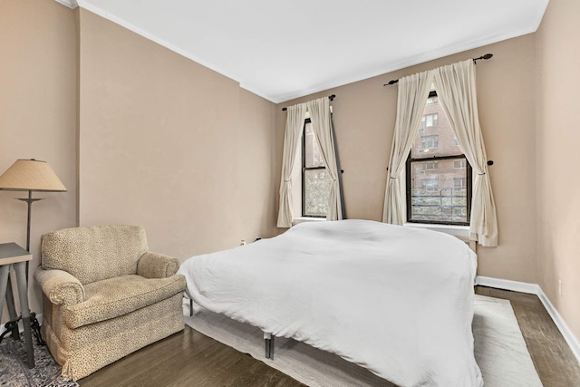 bedroom featuring dark wood finished floors, multiple windows, baseboards, and ornamental molding