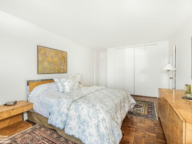 bedroom featuring dark parquet flooring and a closet