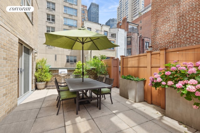 view of patio with outdoor dining area, a city view, and fence