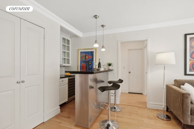 137 E 36th St Unit 2C, New York City, NY 10016 - kitchen featuring a kitchen bar, crown molding, light wood-style flooring, dark countertops, and glass insert cabinets
