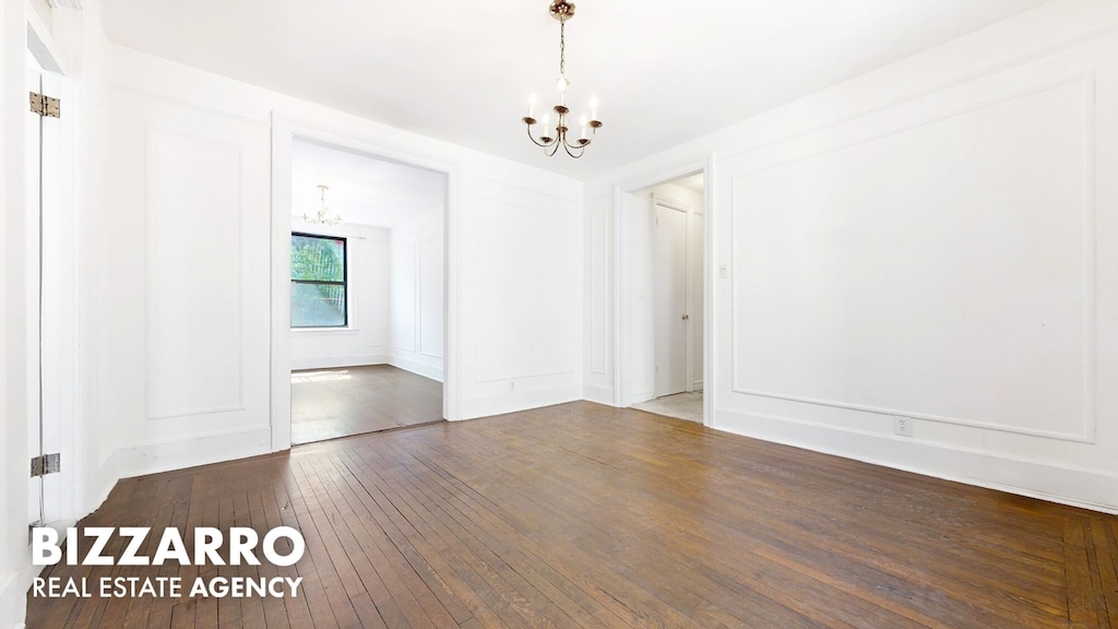 spare room with a chandelier and hardwood / wood-style flooring