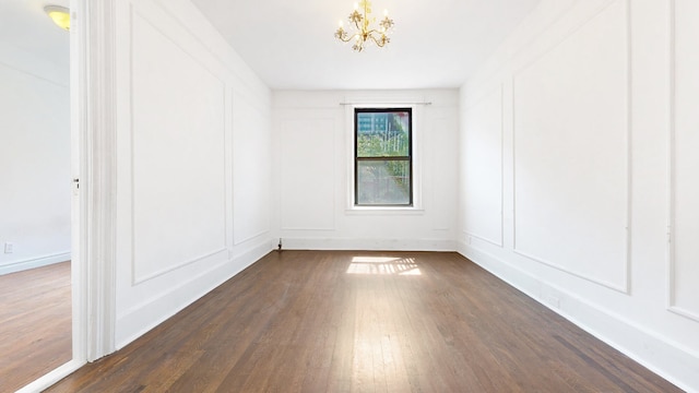 unfurnished room featuring dark hardwood / wood-style floors and an inviting chandelier