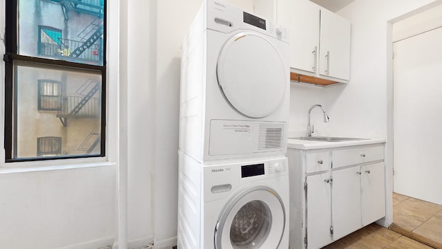 washroom featuring sink, cabinets, and stacked washing maching and dryer