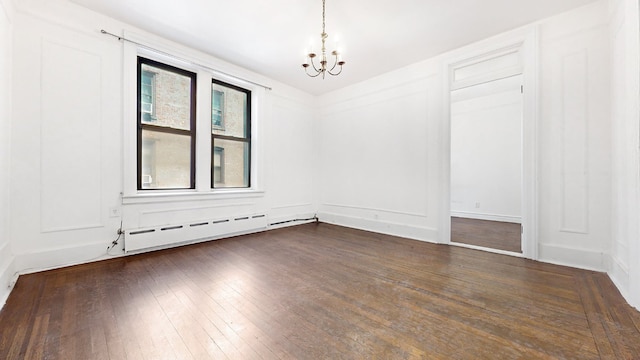 spare room featuring a baseboard heating unit, a notable chandelier, and dark hardwood / wood-style floors