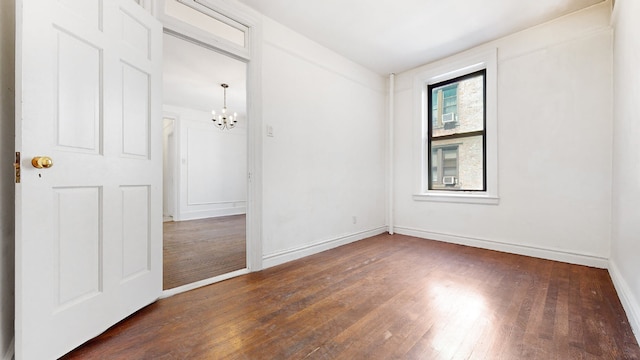 unfurnished room with an inviting chandelier and dark hardwood / wood-style flooring