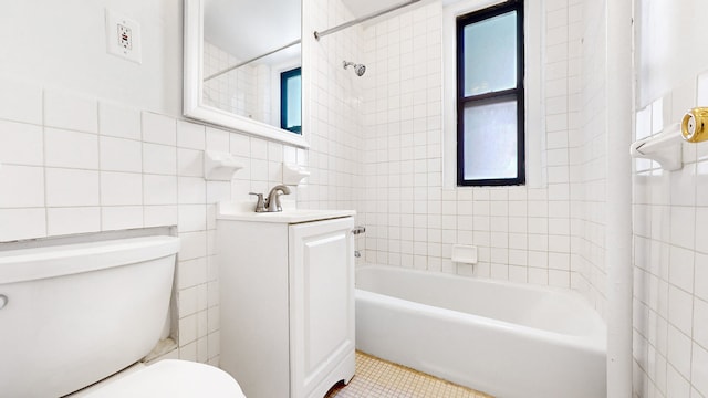 full bathroom featuring tiled shower / bath, tile walls, vanity, toilet, and tile patterned floors