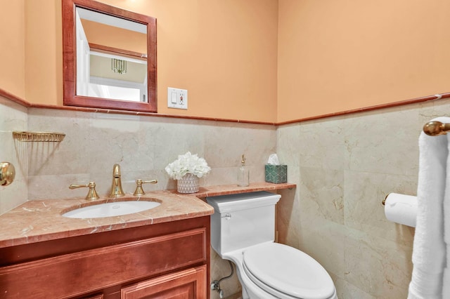 half bathroom featuring tile walls, toilet, vanity, and wainscoting