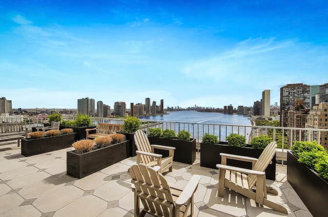 view of patio featuring a skyline view, a water view, and a balcony