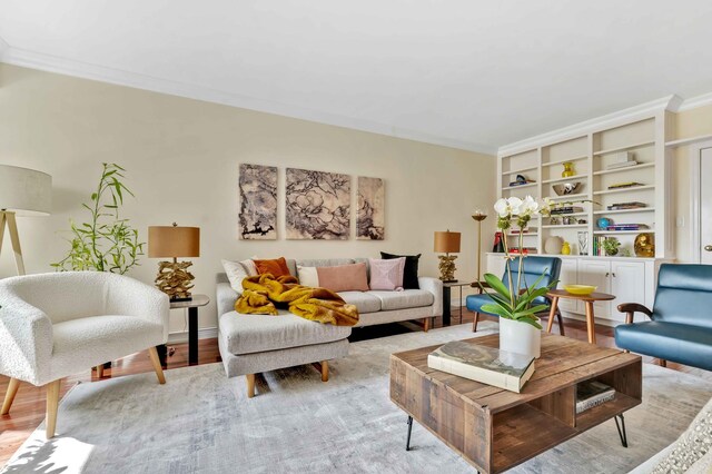 living area with ornamental molding, light wood-style flooring, and baseboards