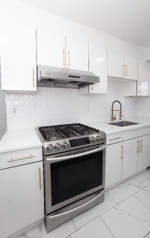 kitchen featuring tasteful backsplash, gas range, sink, and white cabinets