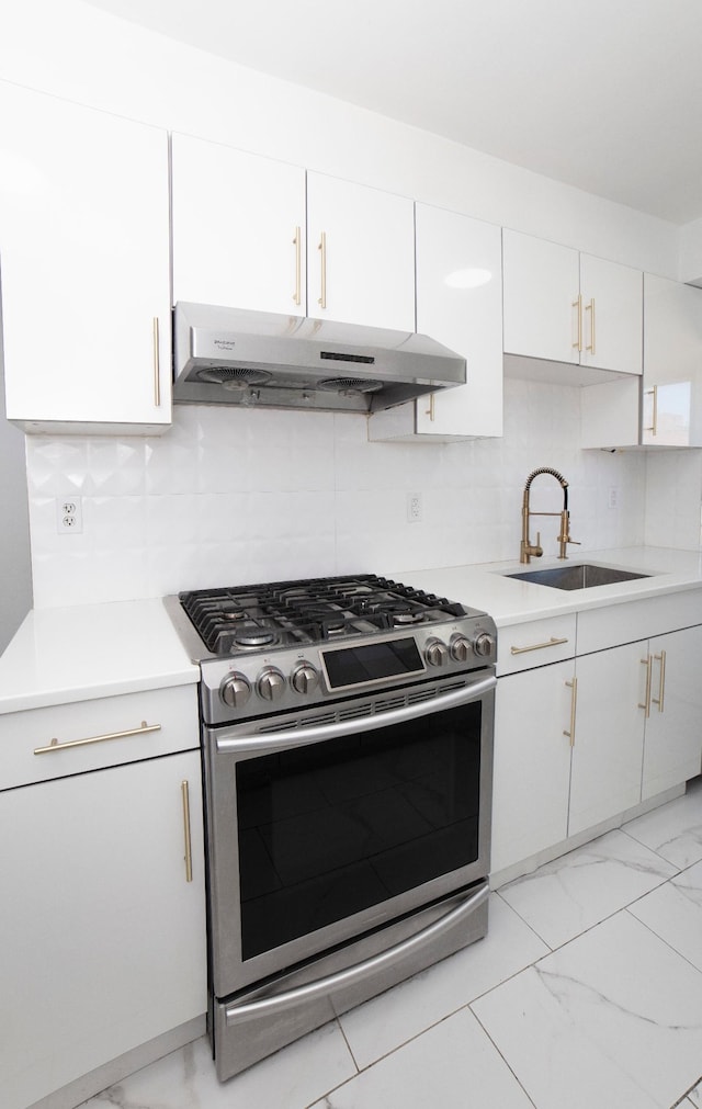 kitchen featuring light countertops, stainless steel range with gas stovetop, a sink, white cabinetry, and under cabinet range hood