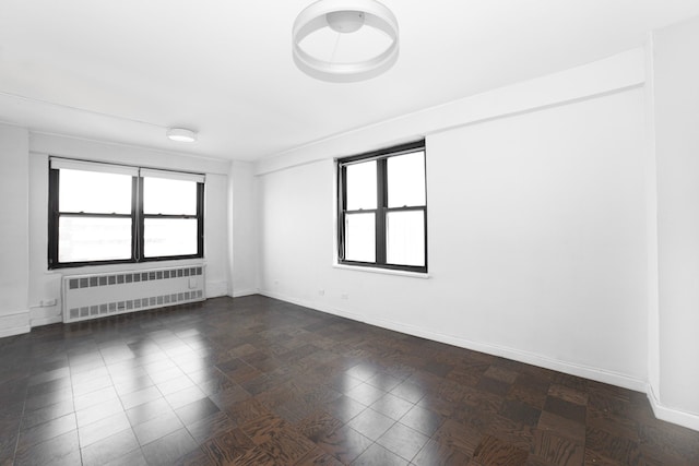 unfurnished room featuring radiator and baseboards