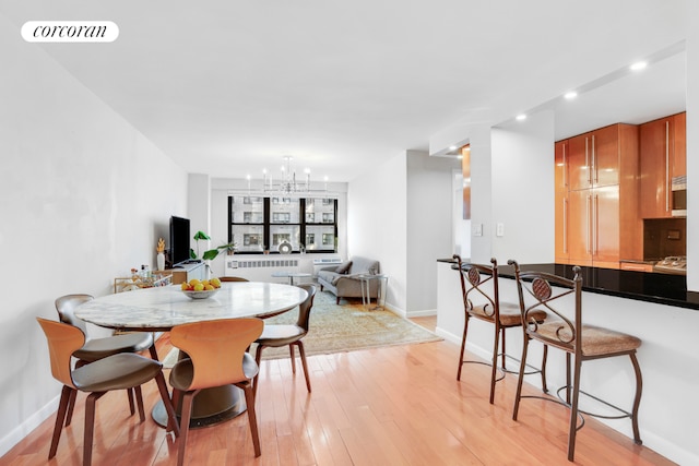 dining area with light hardwood / wood-style floors, radiator, and a chandelier