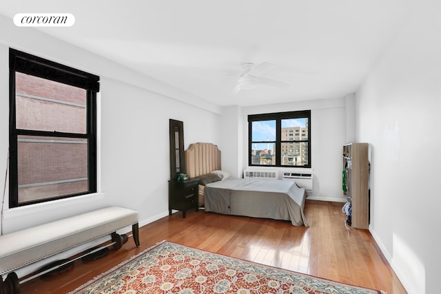 bedroom featuring wood-type flooring, visible vents, radiator heating unit, a ceiling fan, and baseboards