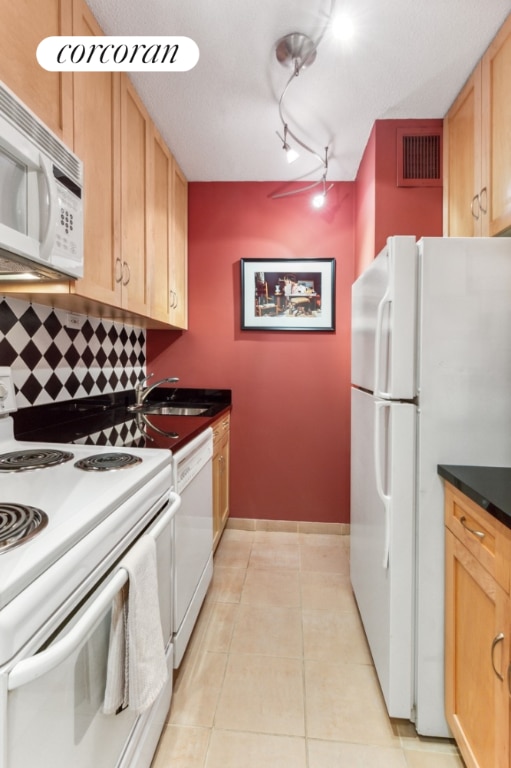 kitchen featuring sink, white appliances, backsplash, track lighting, and light tile patterned flooring