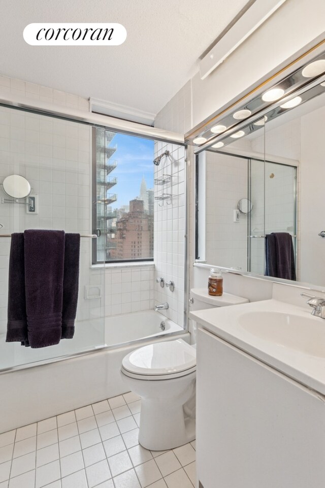 full bathroom with bath / shower combo with glass door, toilet, tile patterned floors, and vanity