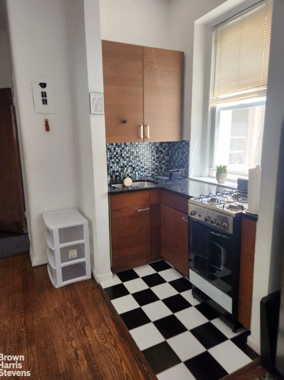 kitchen with tasteful backsplash, dark hardwood / wood-style floors, sink, and white gas range oven