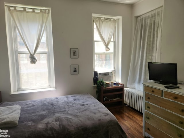 bedroom with dark wood-type flooring, radiator heating unit, multiple windows, and cooling unit