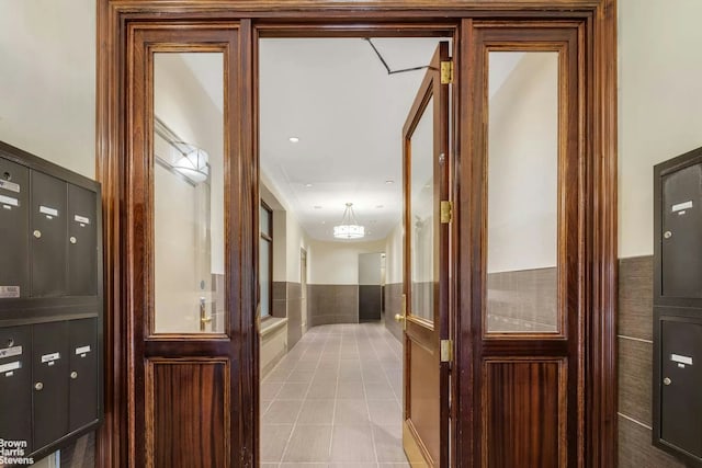 corridor featuring a wainscoted wall, mail area, and tile patterned floors