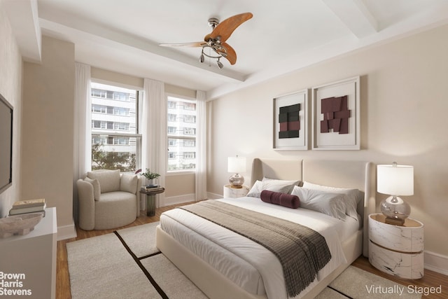 bedroom with beam ceiling, ceiling fan, and light hardwood / wood-style floors