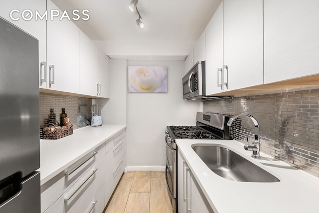 kitchen featuring light countertops, backsplash, appliances with stainless steel finishes, white cabinetry, and a sink