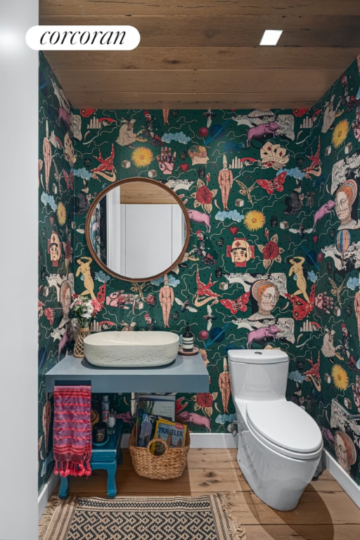 half bathroom featuring wooden ceiling, toilet, a sink, wood finished floors, and baseboards