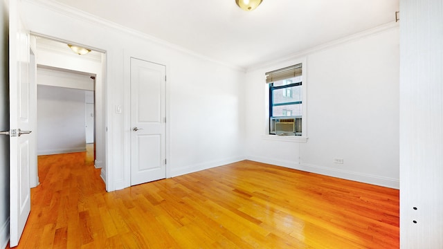 unfurnished bedroom with ornamental molding, light wood-style floors, baseboards, and cooling unit