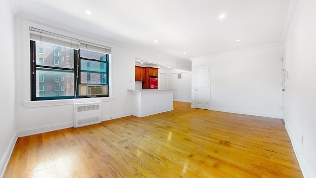 unfurnished living room with radiator heating unit, light wood-type flooring, crown molding, cooling unit, and baseboards