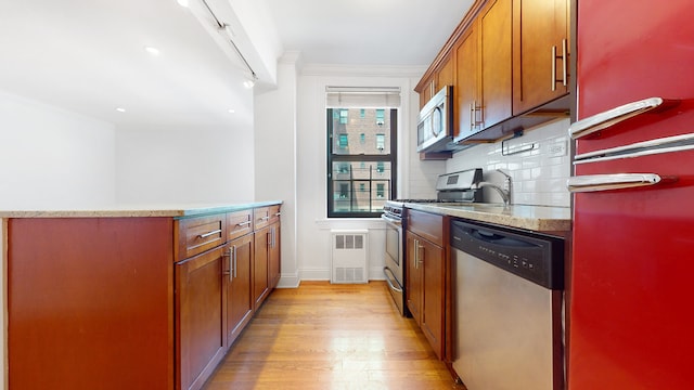 kitchen with appliances with stainless steel finishes, light wood-style flooring, brown cabinetry, decorative backsplash, and baseboards