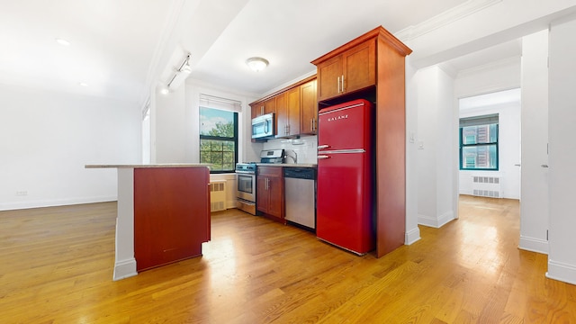 kitchen featuring stainless steel appliances, radiator, ornamental molding, light wood finished floors, and baseboards