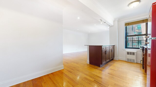 unfurnished living room featuring cooling unit, ornamental molding, radiator, and light wood-type flooring