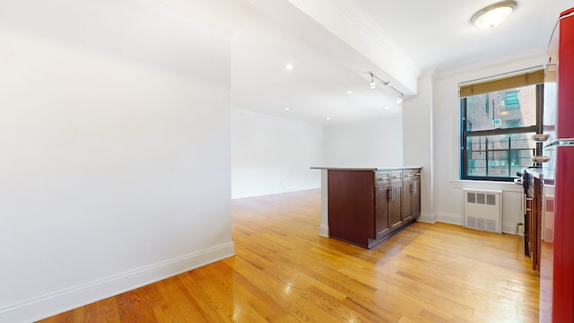 kitchen with light wood-style flooring, radiator, crown molding, a peninsula, and baseboards