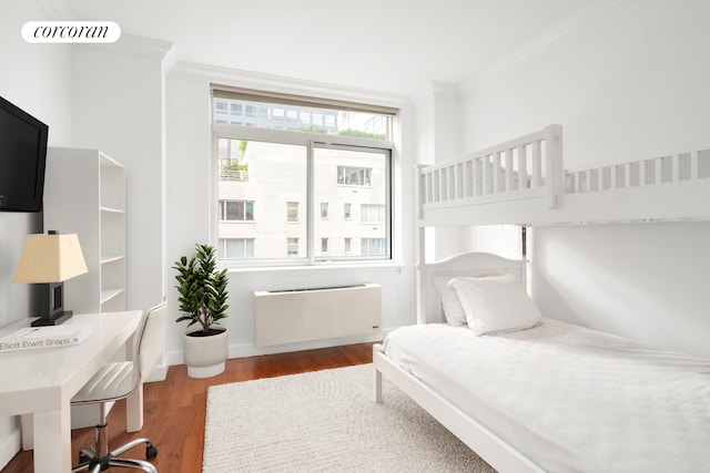 bedroom featuring crown molding, radiator, baseboards, and wood finished floors