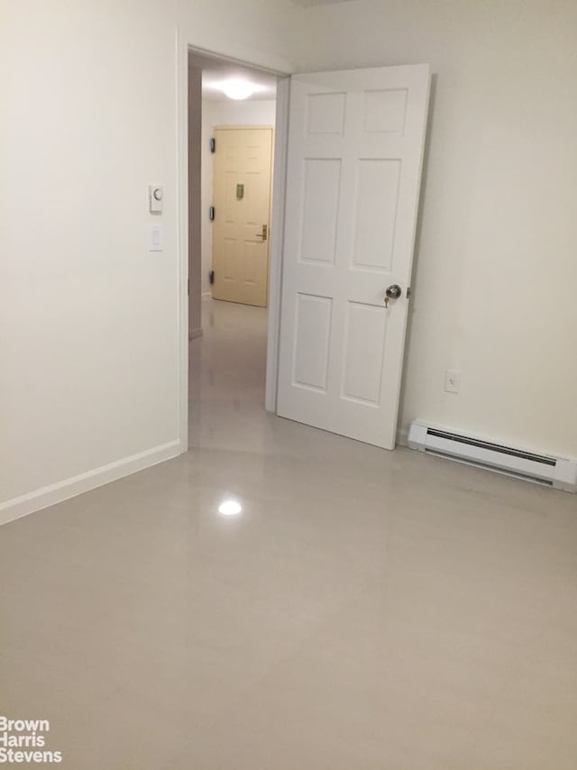 spare room featuring a baseboard heating unit and baseboards