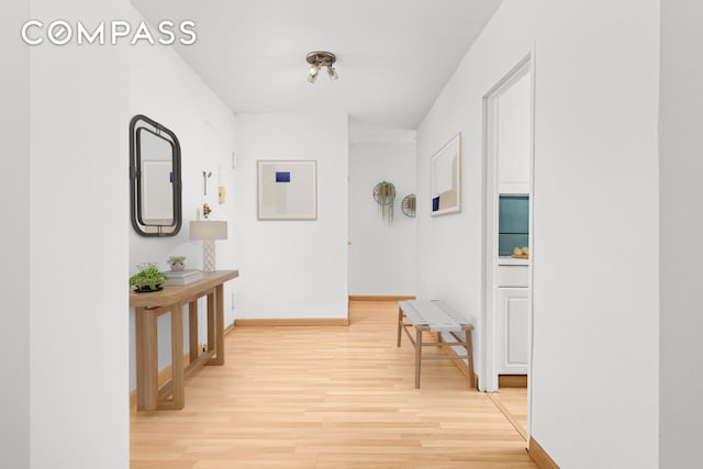 corridor with light wood finished floors and baseboards