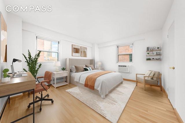 bedroom with baseboards, wood finished floors, and a wall unit AC