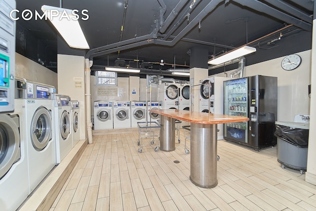 common laundry area with stacked washing maching and dryer, wood finished floors, and washing machine and dryer
