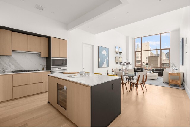 kitchen with light wood-style floors, modern cabinets, light brown cabinets, wine cooler, and stainless steel microwave