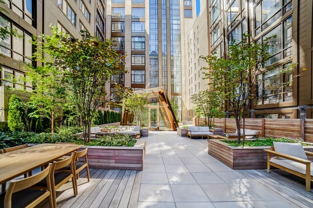 view of home's community featuring outdoor lounge area, outdoor dining space, a wooden deck, and a garden